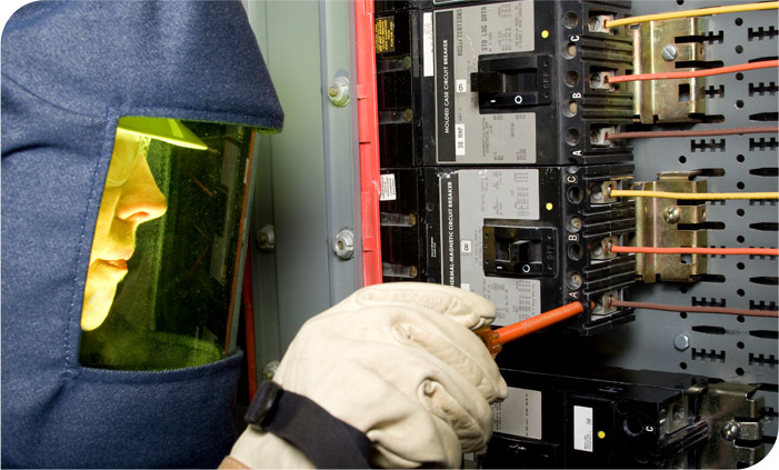 Traditional electrician in safety gear working in an electrical panel